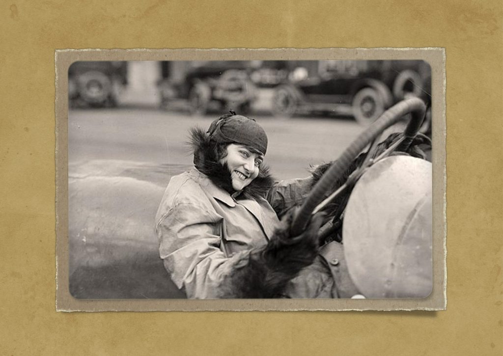 Auf einem antiken Foto wird eine Dame hinter dem Steuer eines Autos gezeigt. Feedbackfahrt